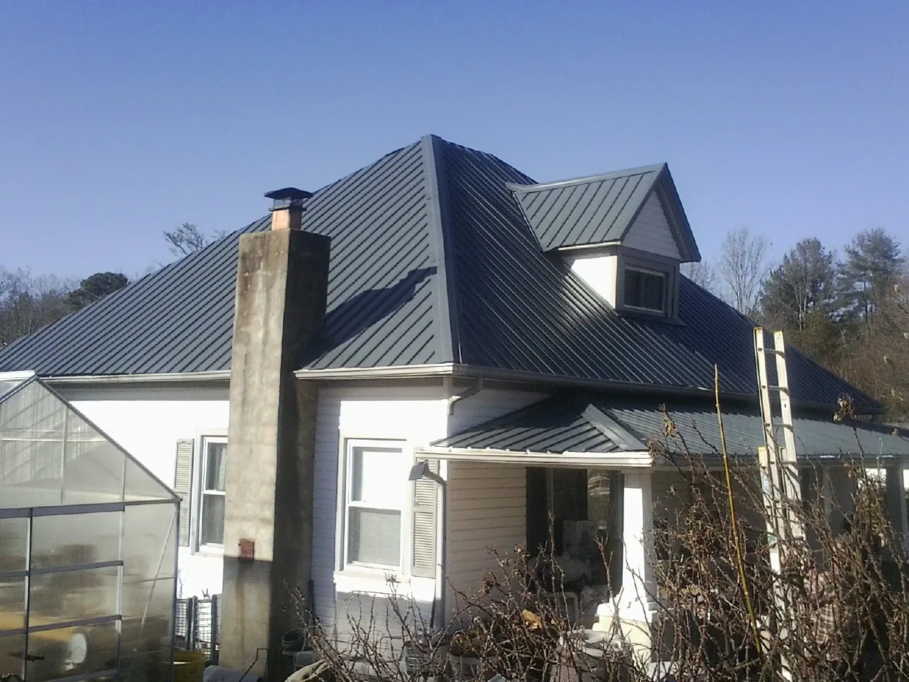Dark blue standing seam metal roof on a white farmhouse with dormer — Slate & Tile Roof Repair by Roofing Brothers in Highland Falls