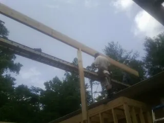 Carpenter setting a ridge beam over a new addition frame — Ice Dam Removal by Roofing Brothers in Highland Falls
