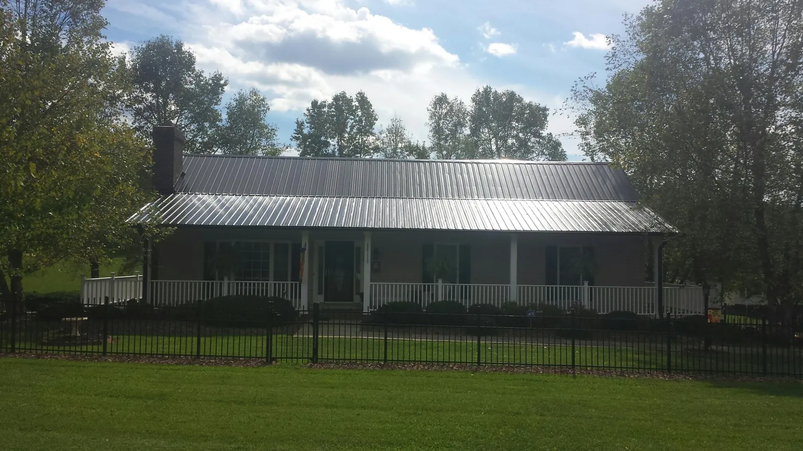 Gray metal roof on a brick ranch with a full width front porch — Gutter Guard Installation work by our crew in Highland Falls