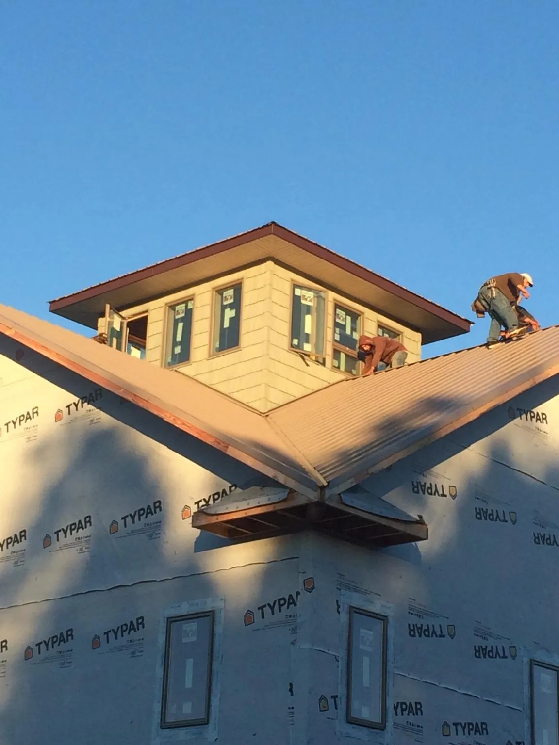 Roofers working around a rooftop cupola on a new metal roof at sunset — Roof Waterproofing in Highland Falls by Roofing Brothers